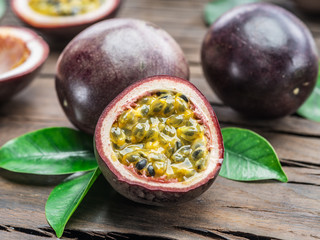 Passion fruits and its cross section with pulpy juice filled with seeds. Wooden background.