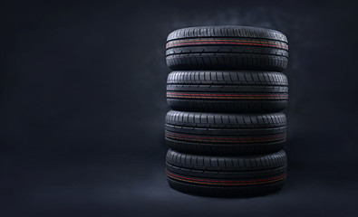 Fototapeta na wymiar New tires pile on a dark background. Copy space.