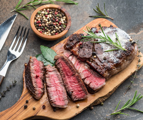 Medium rare Ribeye steak with herbs and a piece of butter on the wooden tray.