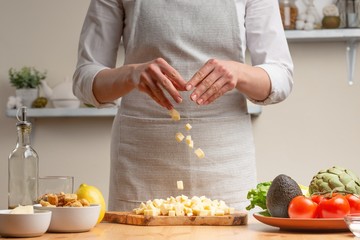 Cooking. A chef pours mozzarella or feta cheese, in the process of a vegetarian salad in the home...