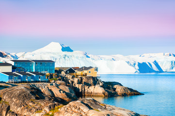 Shore of Atlantic ocean with icebergs in Ilulissat town at sunrise, western Greenland. © smallredgirl