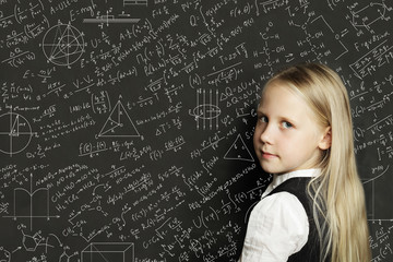Cute smart child student on blackboard background with science formulas. Learning science concept.