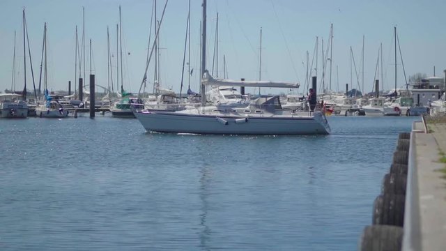 Sailing vessel leaving harbour by motor on a sunny day