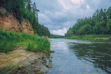 City Cesis, Latvia Republic. Red rocks and river Gauja. Nature  and green trees in summer. Jul 5. 2019 Travel photo.