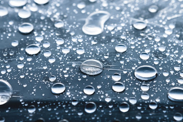Close-up of raindrops of different sizes on the surface covered with cling film. Moisture weather...