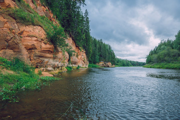 City Cesis, Latvia Republic. Red rocks and river Gauja. Nature  and green trees in summer. Jul 5. 2019 Travel photo.