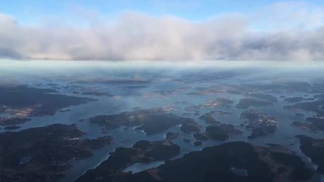 view from an airplane flying above islands and town in the same height with the clouds