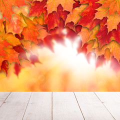 Naklejka na ściany i meble Colorful fall background. Autumn maple leaves and abstract sun light with empty white wooden board background