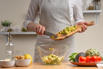 Cooking. The chef pours avocado, in the process of a vegetarian salad in the home kitchen. Light background. Restaurant menu, menu, recipe book. Healthy nutrition, detox