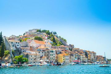 City of Sibenik on the Adriatic coast in Dalmatia, Croatia, fishing and sailing boats in harbor, old town in background - obrazy, fototapety, plakaty