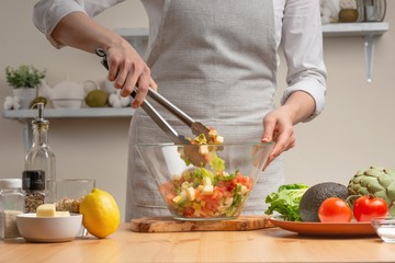 Cooking. The chef is pissed, in the process of a vegetarian salad in the home kitchen. Light background. Restaurant menu, menu, recipe book. Healthy nutrition, detox