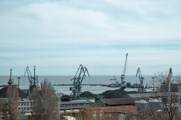 working cranes in the port in cloudy weather. The work of the industrial port in gray weather.