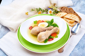 Homemade chicken bouillon with chicken drumsticks on a grunge blue background