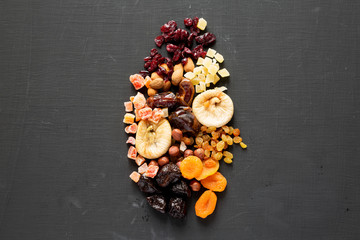 Dried fruits and nut mix on a black surface, top view. Overhead, flat lay, from above. Copy space.