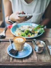 Woman's hand taking photo of coffee cup on wooden table by smartphone