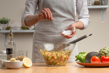 Cooking. Chef salt salad, in the process of vegetarian salad in the home kitchen. Light background....