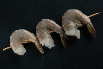 Top view of three raw shrimps on the skewer - obrazy, fototapety, plakaty