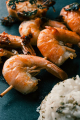 Cooked shrimps on skewers and rice placed near