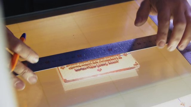 worker makes marks on stencil with pen and ruler close view
