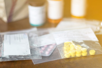 Prescription order from hospital doctor with medicines, drug in plastic zip bags and yellow bottle for chronic patient. Antibiotics , paracetamol, vitamins supplement dosage on white background.