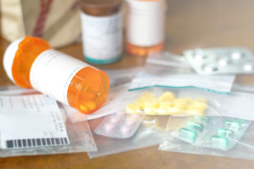 Prescription order from hospital doctor with medicines, drug in plastic zip bags and yellow bottle for chronic patient. Antibiotics , paracetamol, vitamins supplement dosage on white background. © Khunatorn