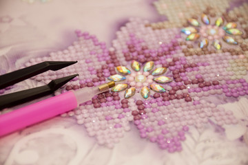 Obraz na płótnie Canvas Diamond painting embroidery craft. Acrylic rhinestones. Closeup, selective focus