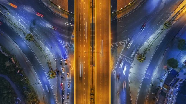 Hyperlapse timelapse of night city traffic on 4-way stop street intersection circle roundabout in bangkok at night, thailand. 4K UHD horizontal aerial view.