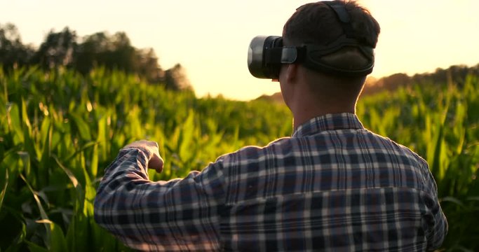 Smart farming with IoT, futuristic agriculture concept : Farmer wears VR or AR glasses while monitoring rainfall, temeprature, humidity, soil pH with immersive experience on digital holographic screen