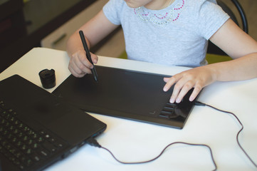 child draws on a graphic tablet