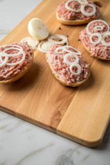 Deutsche Mettbrötchen mit rohen Schweine Mett, Brötchen, Butter, Zwiebeln, Pfeffer und Mett auf Holzbrett mit Messer in Küche