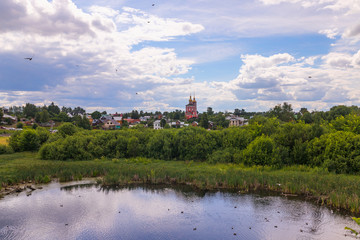 Fototapeta na wymiar Rural landscape with houses, church, pond and summer greenery, Suzdal, Russia
