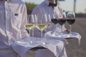 Catering service. A waiter is holding a wine on a wine tray.