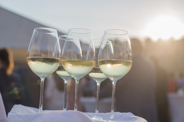 A waiter is holding a tray with glasses of white wine for a party and tasting in honor of the harvest festival. Catering service.