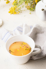 Close up of yellow herbal tea in white cup. Herbal medicine. Natural dietary supplement . Saint-John's-wort tea