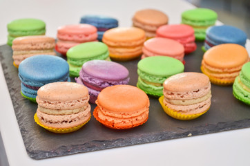 Fototapeta na wymiar Different sweet colored macarons pastry on a black stone plate at a banquet