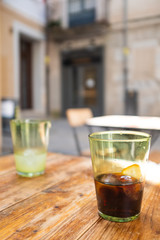 Brown vermouth on a drinking glass with ice cubes on a wooden table