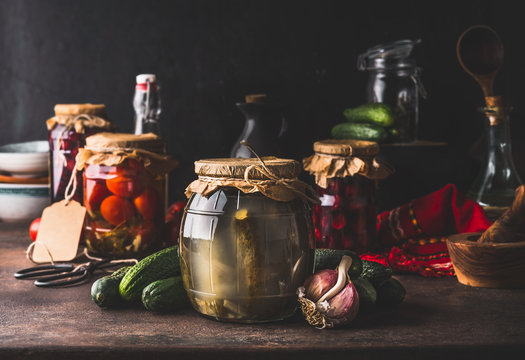 Harvest preserve concept. Glass jars with fermented, pickled and canned vegetables and fruits on dark rustic kitchen table. Conservation of farm organic seasonal harvest. Healthy homemade food