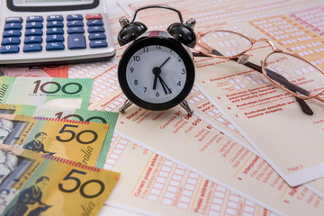 Australian dollars, clock and calculator on tax form