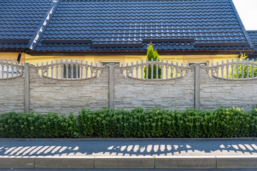 A fence made of grey concrete blocks with decorative greenery
