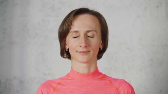 Portrait of young woman in pink turtleneck opens and closes her eyes portraying an emotion of surprise. Big eyes and smiling face on video portrait.