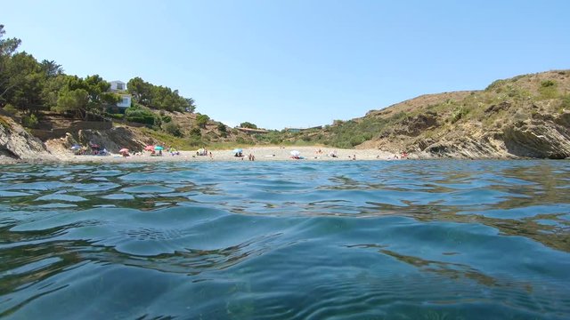 Spain Mediterranean cove with pebble beach seen from sea surface and seagrass underwater, summer vacation, Costa Brava, Cadaques, Cap de Creus, Catalonia