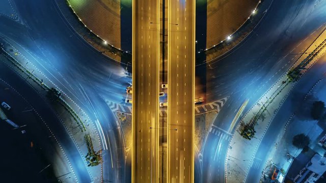 Hyperlapse timelapse of night city traffic on 4-way stop street intersection circle roundabout in bangkok at night, thailand. 4K UHD horizontal aerial view.