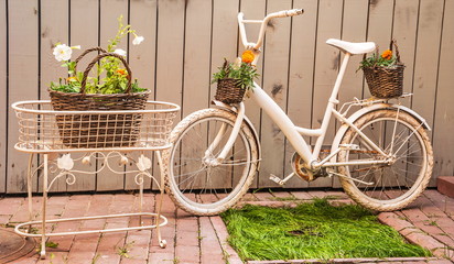 Fototapeta na wymiar Garden decorative composition from old bicycle and baskets of flowers