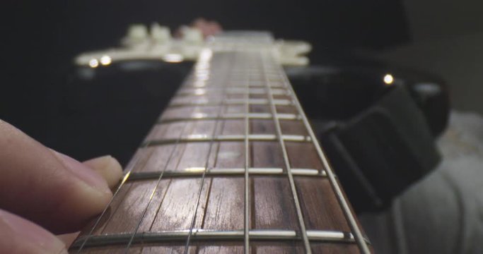 Closeup shoot of old guitar with strings being hold by a musician with background isolated on black