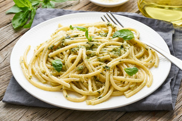Pesto spaghetti pasta with basil, garlic, pine nuts, olive oil. Rustic table, close up