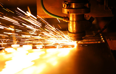 Bright blaze and sparkles while automated laser device cutting steel