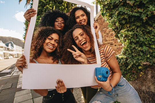 Excited friends with blank photo frame