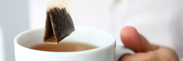 Man in white shirt stirring traditional healthy ceylon tea in cup