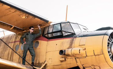 A handsome young pilot standing on the wing of a plane