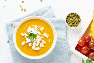 Pumpkin cream soup with feta cheese, autumn homemade food, white background, top view